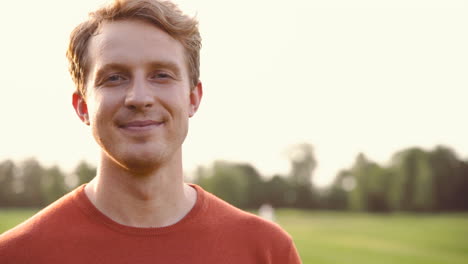 portrait of a man smiling and looking at camera in the park 2