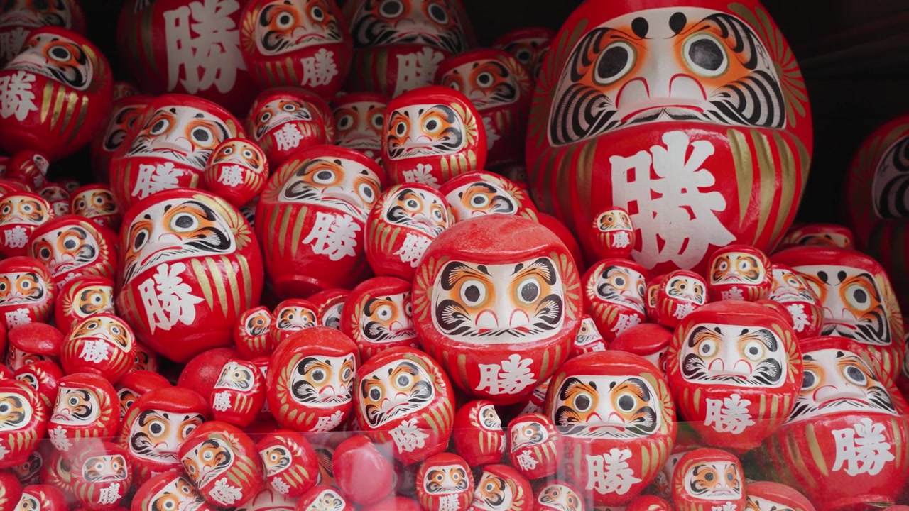 Un video ravvicinato di centinaia di bambole Daruma rosse esposte al Tempio Katsuoji a Osaka, Giappone, che mostrano un simbolo tradizionale giapponese associato a buona fortuna, perseveranza, desideri e successo.