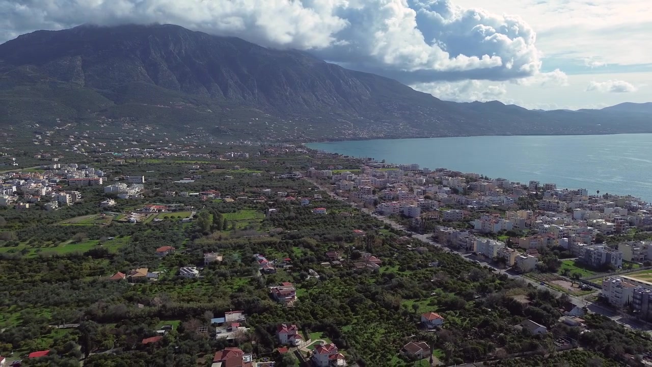 Aéreo, afastando e subindo, plano de estabelecimento, mar de Kalamata, nuvens sobre a montanha Taygetos ao fundo 4k