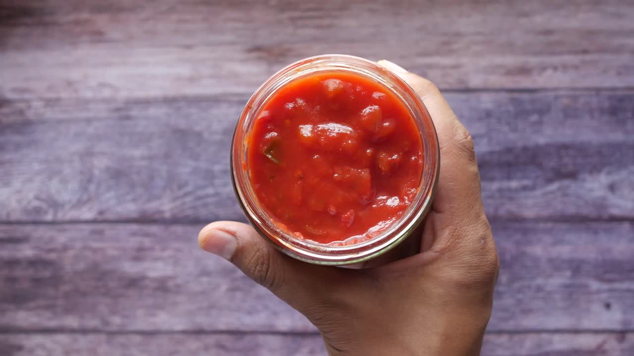 mano con un frasco de salsa de tomate