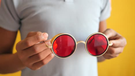 person holding round red sunglasses