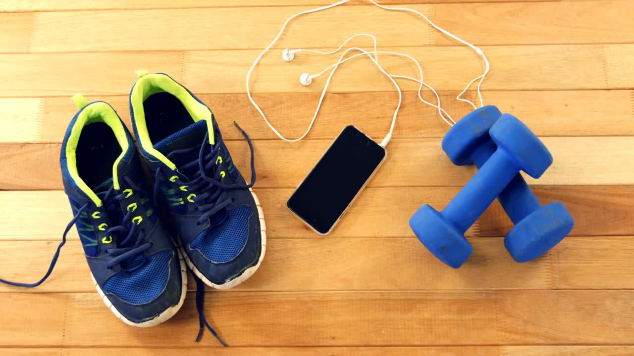 Ponsel dengan headphone, sepatu, dan dumbbell