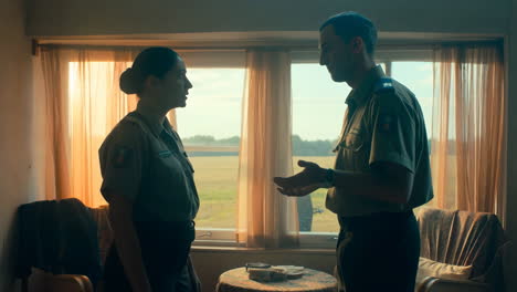 Two uniformed officers engaged in a conversation by a window