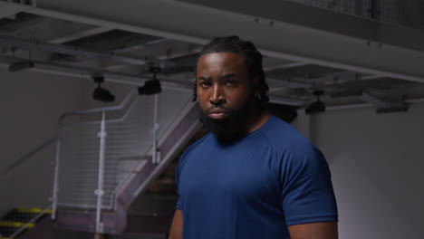 portrait of determined male athlete sport training in gym standing and concentrating in changing room with focused expression