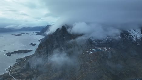 flying over extreme foggy reine mountain peaks overlooking picturesque wintry blue ocean