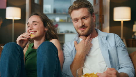 gente riendo divirtiéndose en el interior pov. pareja emocional viendo televisión comiendo