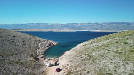 Beautiful-wild-cove-with-a-beach-and-deep-clear-blue-sea-in-the-white-karst-of-Zadar-region,-Croatia-from-above