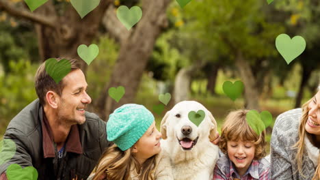múltiples iconos de corazón rosa flotando contra la familia caucásica con su perro mascota en el parque