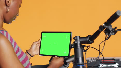 mecánico haciendo el mantenimiento de la bicicleta, mirando la tableta de pantalla verde