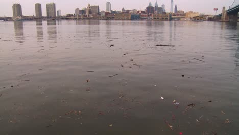 tilt up to ugly brown pollution in a river with philadelphia pennsylvania background