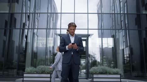 confident businessman holding smartphone getting great news. success concept.