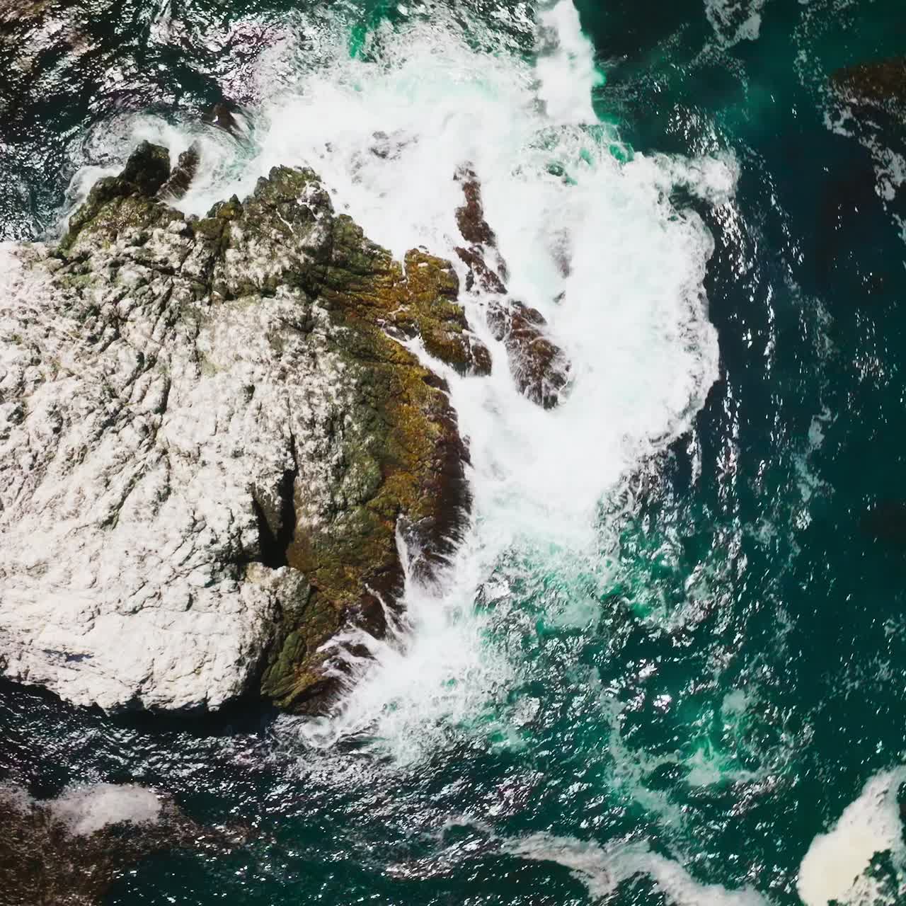 Roccia frastagliata e irregolare nell'oceano blu. Onde bianche che si infrangono sulla scogliera ricoperta di sale marino. Vista dall'alto