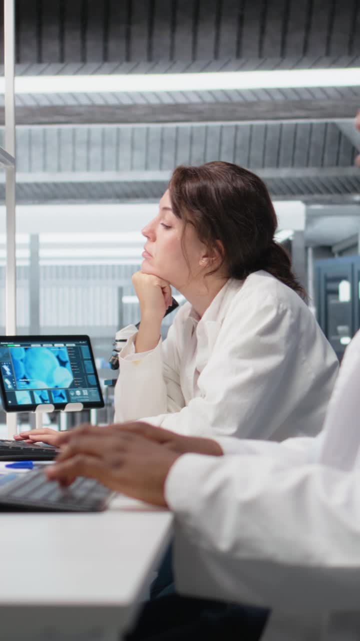 Vertical video Laboratory manager oversees scientists working on computer