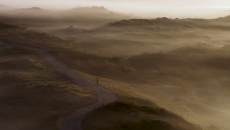 misty sunrise over dunes with cycling path