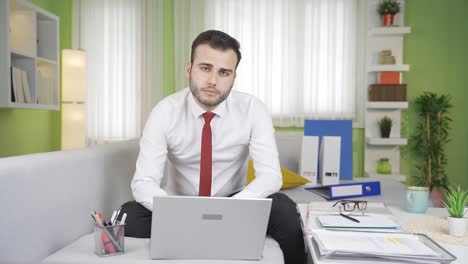 young businessman working at home looking at camera.