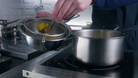 chef cook in apron takes out ravioli from pot