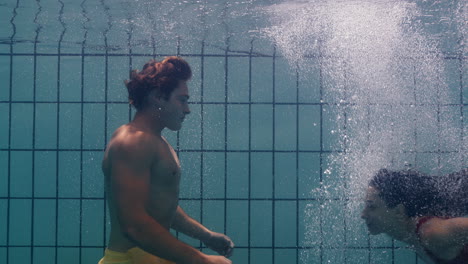 una pareja submarina besándose en la piscina jóvenes enamorados disfrutando de un beso romántico amantes apasionados sumergidos en el agua flotando con burbujas en una intimidad lúdica