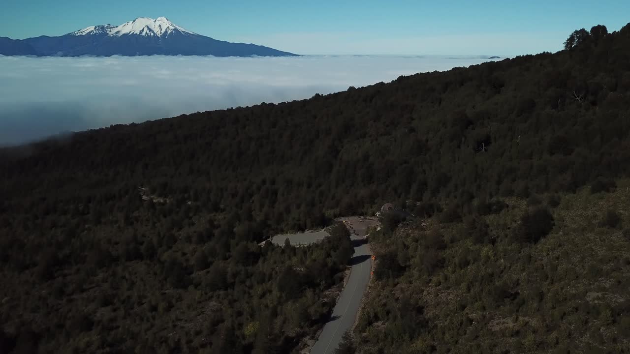 Calbuco Volcano, Chile. Cinematic Drone Aerial View of Road and Clouds in Valley Under Snow Capped Crater