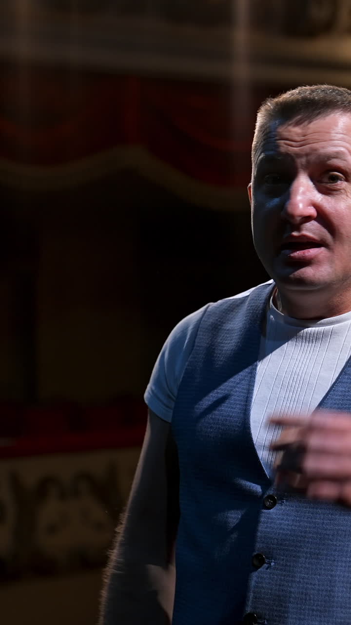 Portrait of a male actor. Middle-aged man speaking during the rehearsal while standing on stage. Comedian in the theater. Vertical video