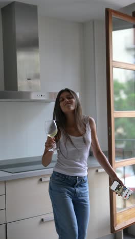 woman dancing in kitchen with wine