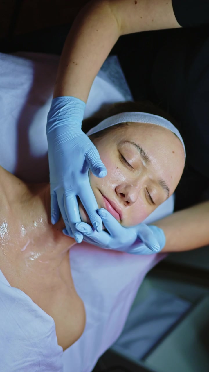 Sessione di trattamento di bellezza per la cura della pelle in una spa con un cliente sdraiato su un lettino mentre un professionista applica una maschera sul viso.
