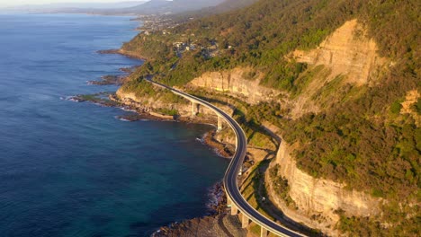 Scenic-Sunrise-View-Of-The-Sea-Cliff-Bridge-In-NSW-Australia-In-Sunrise---aerial-shot