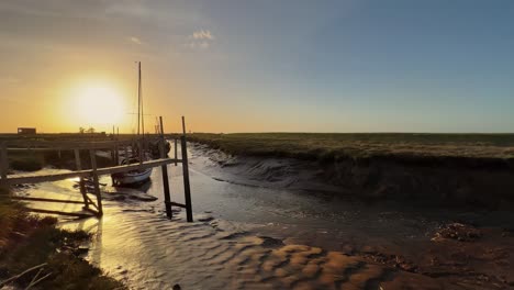 small sailing boat docked in the estuary with evening with golden sunlight