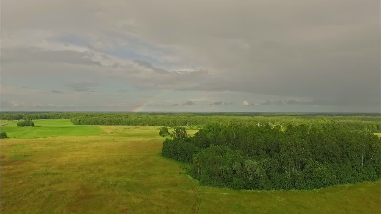 vista aérea de un arco iris colorido en el horizonte en un día nublado sobre un campo