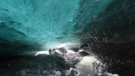 toma estática de una persona caminando en una cueva de hielo dentro de un glaciar oscuro - explorando la naturaleza de islandia, europa