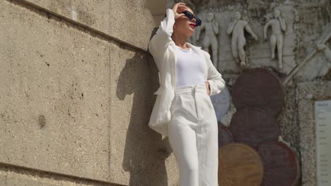 una mujer joven, vestida con un traje de negocios, se encuentra en medio del animado paisaje urbano mientras sostiene sus gafas de sol