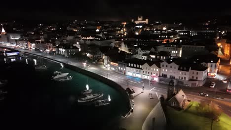 Drohnenflug-über-North-Plantation,-St.-Peter-Port,-Guernsey-Bei-Nacht-Mit-Hafen,-Strandpromenade,-Uhrturm-Und-Brückenwaage-Sowie-Blick-Auf-Die-Stadt-Und-Das-Beleuchtete-Elizabeth-College-Im-Hintergrund