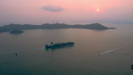 Container-ship-passing-by-an-island-during-a-splendid-sunset