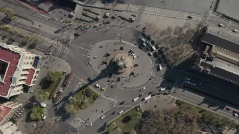 aerial: overhead shot of columbus monument roundabout in barcelona, spain with busy car traffic on sunny day [4k]