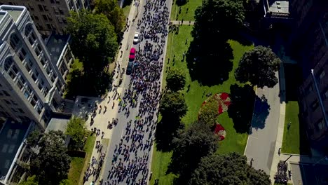 People-walk-by-government-buildings-in-Toronto,-aerial-drone-dolly-in