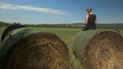 Una-Joven-Negra-En-Guardia-Se-Sienta-Encima-De-Un-Fardo-De-Heno-En-Un-Paisaje-Rural