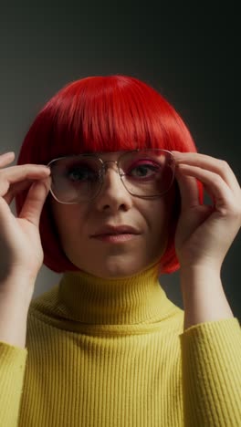 woman with red wig, glasses, and yellow sweater