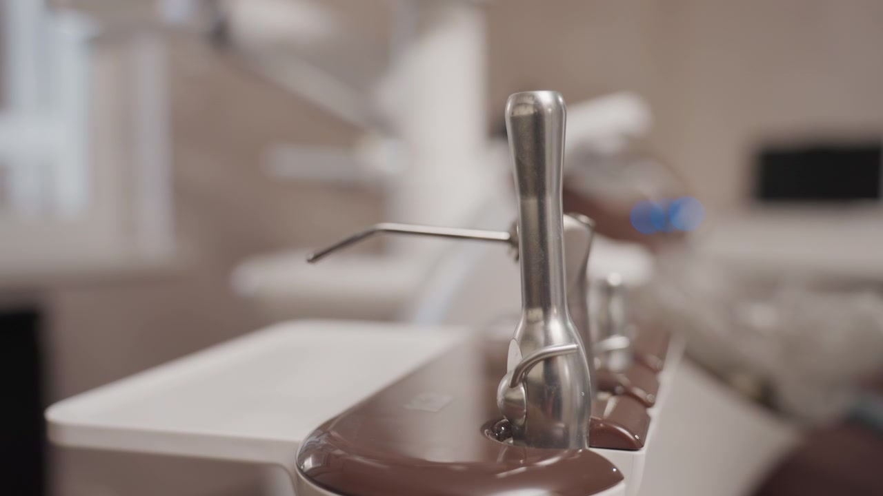 Close up of dental tools resting on tray in orthodontic clinic. scene shows metal instruments with smooth surfaces and reflections positioned steadily against backdrop of blurred medical