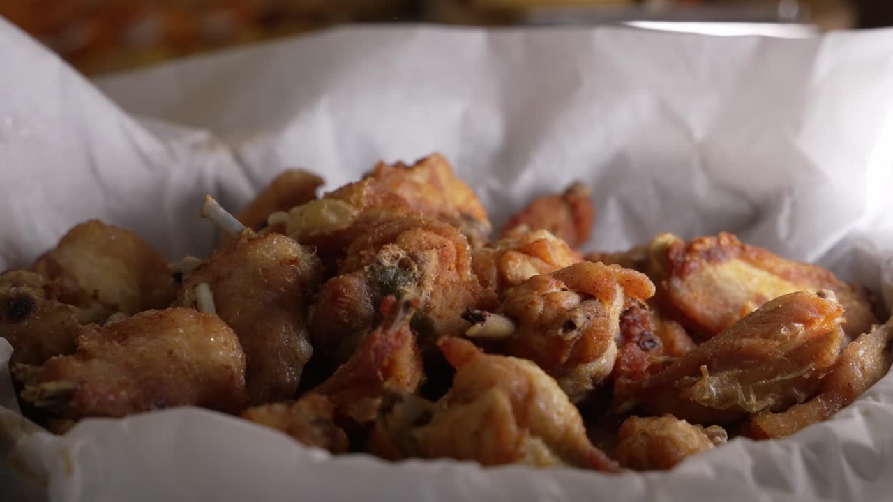 Golden fried chicken wings stacked in a white paper lined serving container