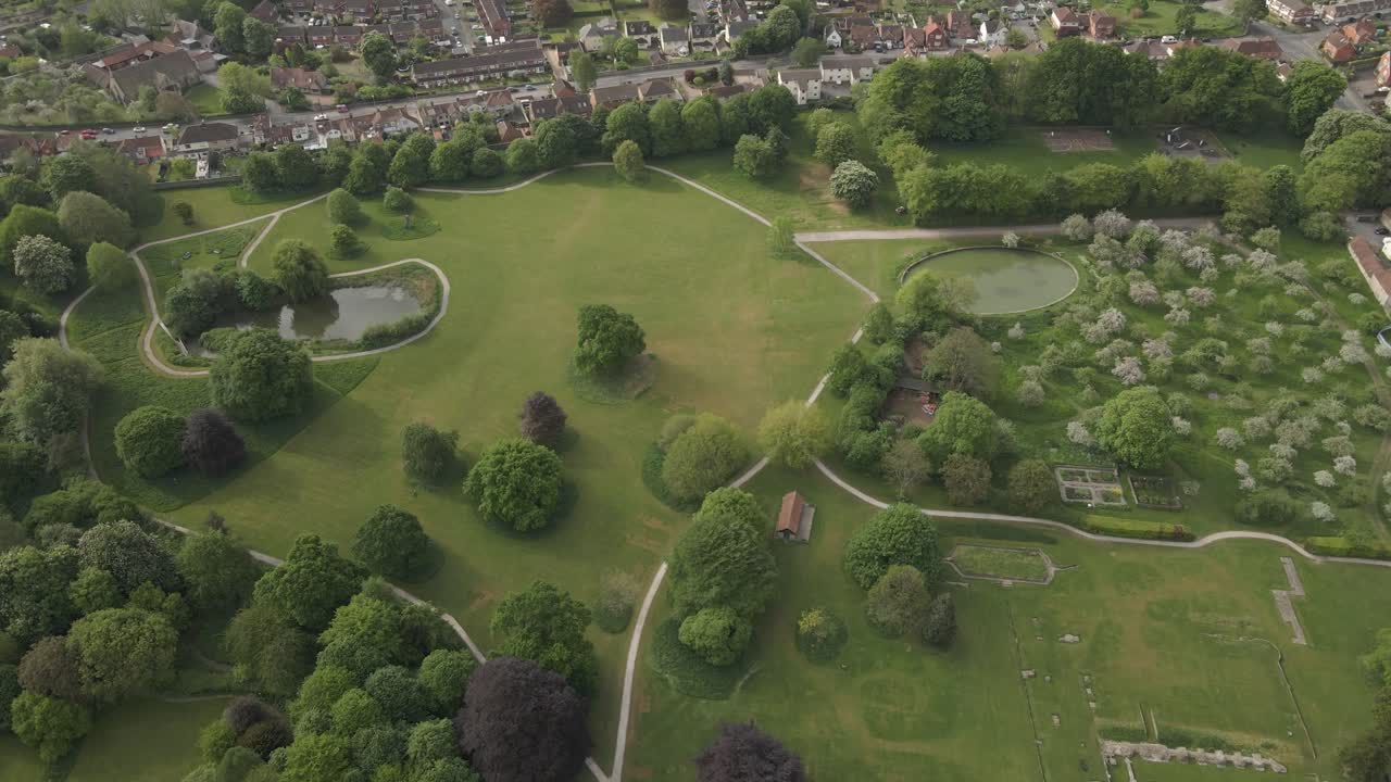Aerial view of Glastonbury abbey ruins, drone moving forward and camera facing down over the abbey gardens and ruins,. 4K, 60fps.