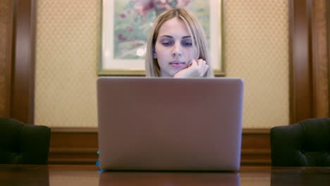 beautiful woman looking on notebook screen sitting at table in home office