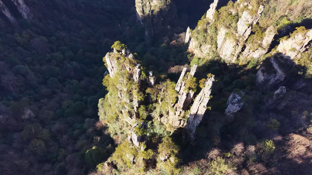 Drone orbits single towering pillar covered in trees, revealing epic Zhangjiajie Avatar landscape in background