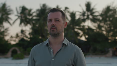 parallax shot of thoughtful man standing in silence on the beach contemplating about life and past during epic sunset.
