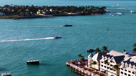 drone following a racerboats driving in front of the key west town, in sunny usa