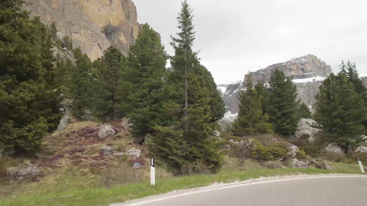 Filmed from a moving vehicle on the Giau Pass, Dolomites. Sharp curves, snowy peaks, and massive mountains create one of the most iconic alpine drives in northern Italy