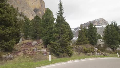 filmed from a moving vehicle on the giau pass, dolomites. sharp curves, snowy peaks, and massive mountains create one of the most iconic alpine drives in northern italy