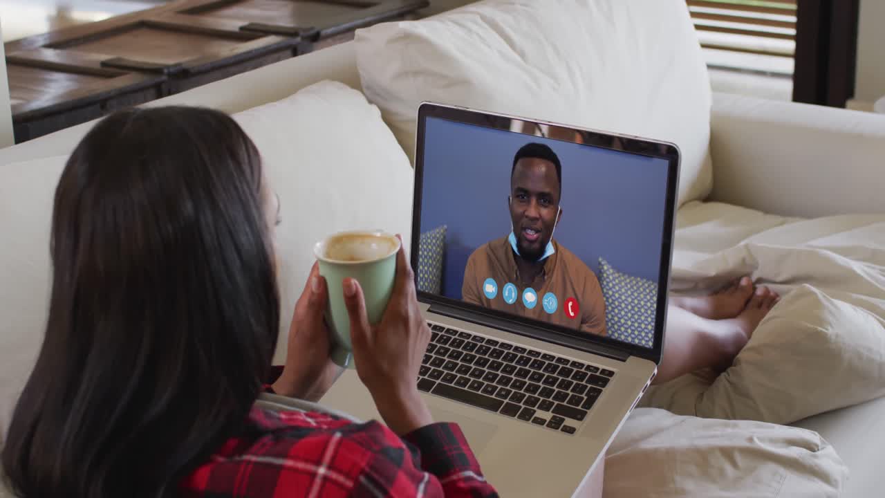 Mixed race woman on laptop video chat having coffee at home
