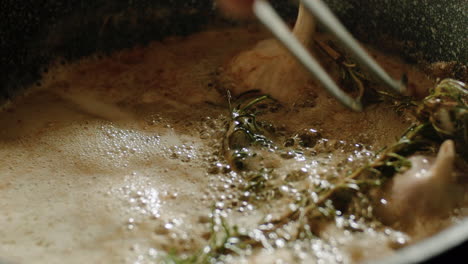 Moving-around-twigs-of-rosemary,-infusing-melted-hot-butter-with-aroma,-garlic-bulbs