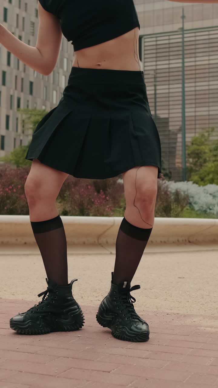 Giovane donna che balla con gonna nera e sneakers per strada in città