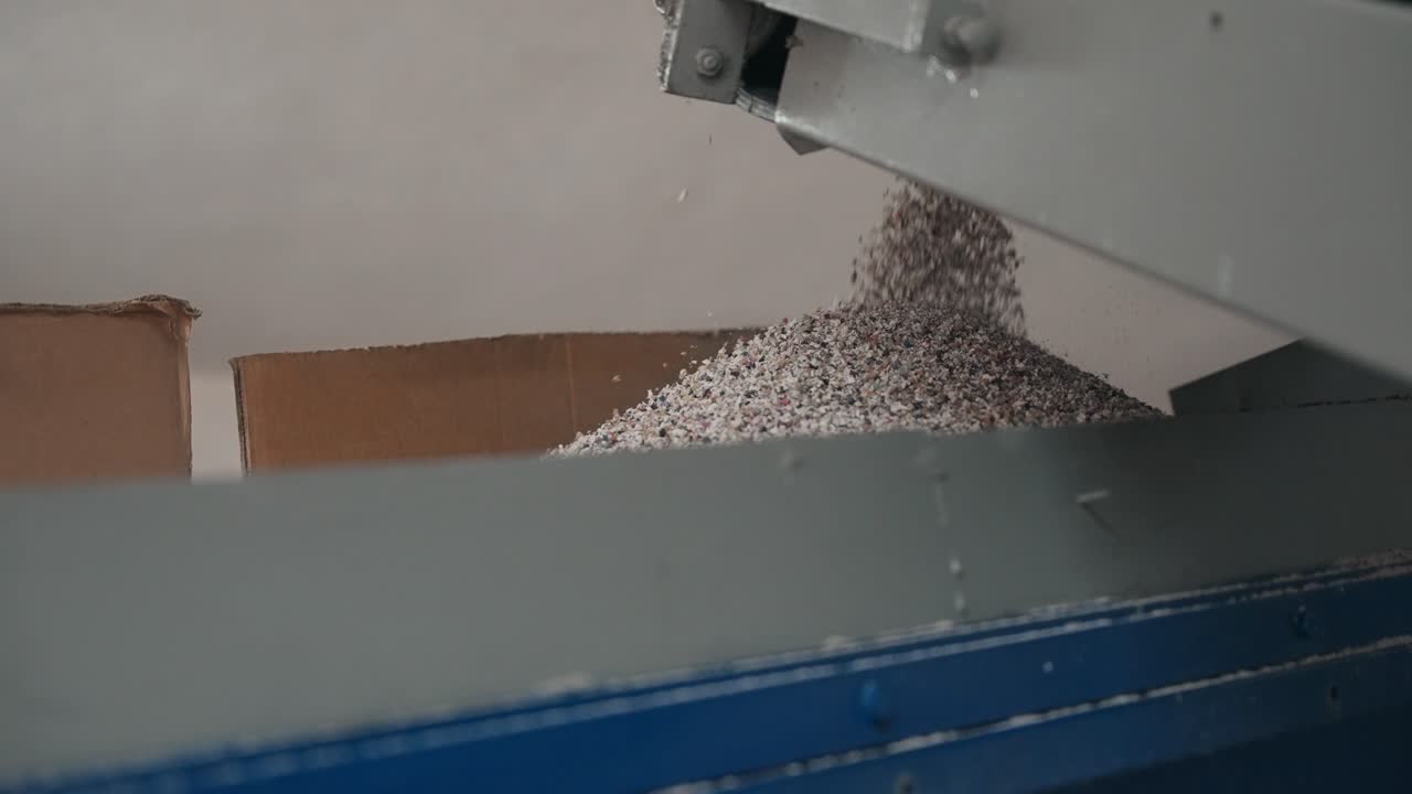 컨베이어에서 공장 보관 상자로 떨어지는 미세한 고무 과립