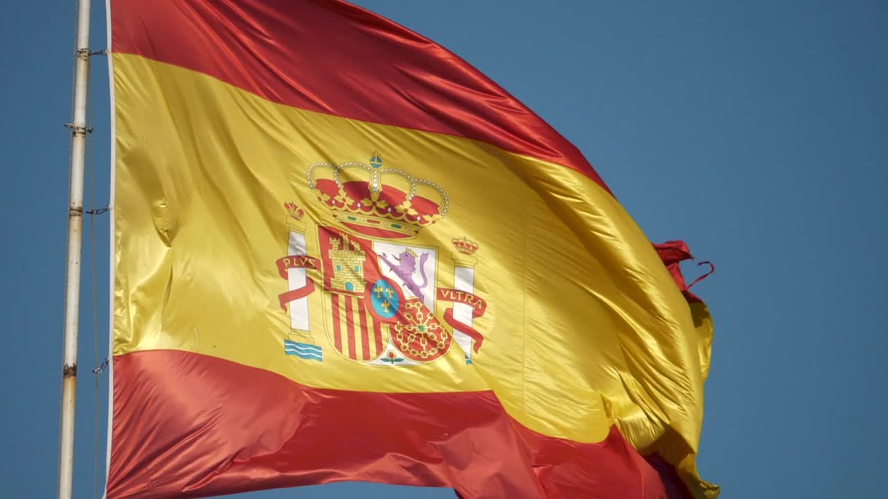 Cámara lenta de la bandera española ondeando al viento y un pájaro volando